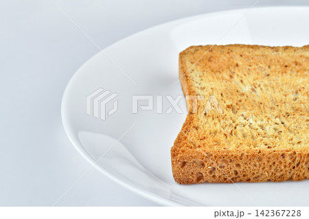 a part of one golden crispy toasted organic whole wheat sandwich bread isolated on white dish and background with very narrow focusing a part of one golden crispy toasted organic whole wheat sandwich bread isolated on white dish and background with very narrow focusing 142367228