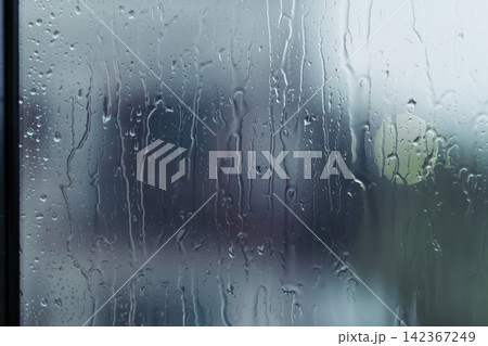 rain drops during raining in rainy day outside window glass with blurred background with water droplet flow down the surface 142367249