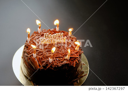 A dark black forest chocolate cake with a Happy Birthday sign sits on a black background A dark black forest chocolate cake with a Happy Birthday sign sits on a black background 142367297