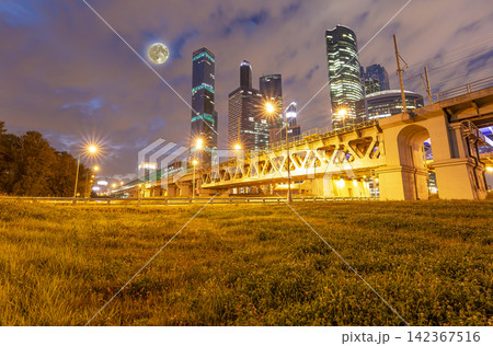 Moscow Central Circle (Little Ring, MCC, or MK MZD) and skyscrapers of the International Business Center (City) at night, with the super moon, Russia. Delovoy Tsentr railway station Moscow Central Circle (Little Ring, MCC, or MK MZD) and skyscrapers of the International Business Center (City) at night, with the super moon, Russia. Delovoy Tsentr railway station 142367516