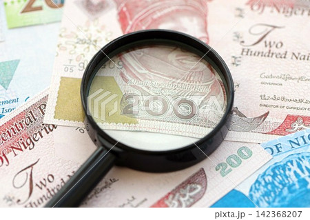 Nigerian naira currency money bills and magnifying glass. The concept of financial monitoring and taxation 142368207