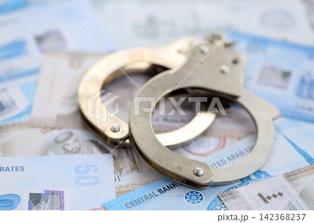 United Arab Emirates dirham currency money bills and handcuffs. The concept of criminal United Arab Emirates dirham currency money bills and handcuffs. The concept of criminal 142368237