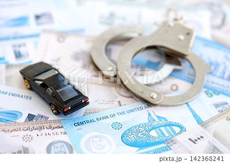 United Arab Emirates dirham currency money bills and toy car with handcuffs. The concept of car accident United Arab Emirates dirham currency money bills and toy car with handcuffs. The concept of car accident 142368241
