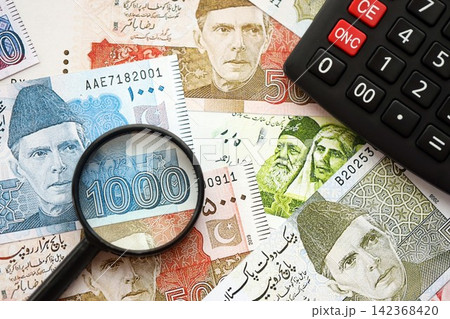 Pakistan rupees banknotes and calculator with magnifying glass. Pakistan money bills calc with loupe Pakistan rupees banknotes and calculator with magnifying glass. Pakistan money bills calc with loupe 142368420