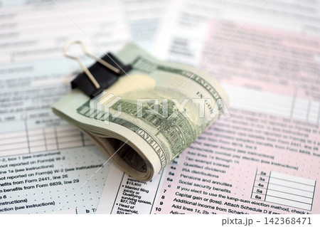 Big amount of United States hundred dollar bills on table with tax return form close up Big amount of United States hundred dollar bills on table with tax return form close up 142368471
