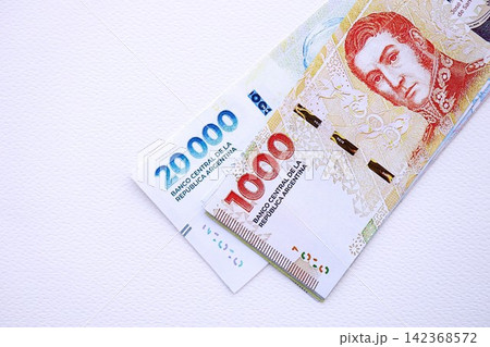 Argentine pesos money bills in big amount lies on white table close up Argentine pesos money bills in big amount lies on white table close up 142368572