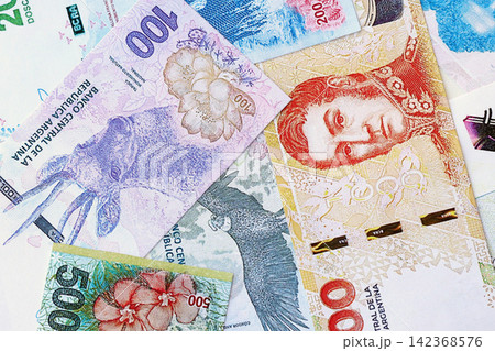 Argentine pesos money bills in big amount lies on white table close up Argentine pesos money bills in big amount lies on white table close up 142368576