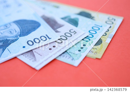 South Korean won money bills in big amount lies on red color table close up South Korean won money bills in big amount lies on red color table close up 142368579
