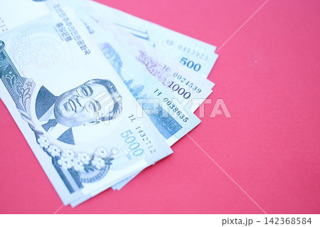 North Korean won money bills in big amount lies on red color table close up 142368584
