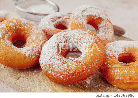 Place the baked donuts on a cutting board, sprinkled with powdered sugar, home cooking, no people, 142368986
