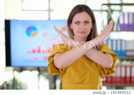 Serious businesswoman crosses arms to signal rejection in office 142369522