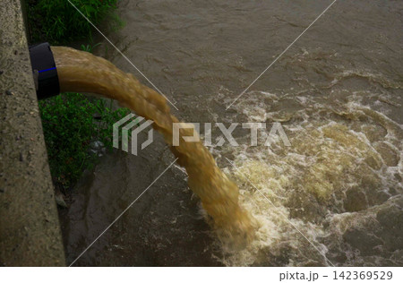 Polluted water runoff flows into a river, harming local ecosystems Polluted water runoff flows into a river, harming local ecosystems 142369529