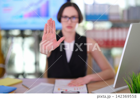 Serious female boss shows Stop hand gesture in corporate office Serious female boss shows Stop hand gesture in corporate office 142369558