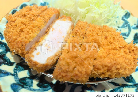 千切りキャベツを添えた黄金色のとんかつと肉の断面を写した料理写真 千切りキャベツを添えた黄金色のとんかつと肉の断面を写した料理写真 142371173