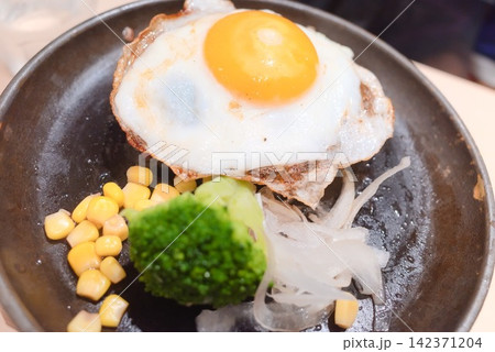 目玉焼きをのせた香ばしいハンバーグと彩り野菜のクローズアップ 目玉焼きをのせた香ばしいハンバーグと彩り野菜のクローズアップ 142371204