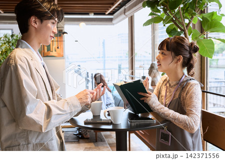 カフェで打ち合わせをする若い男女のビジネスパーソン カフェで打ち合わせをする若い男女のビジネスパーソン 142371556