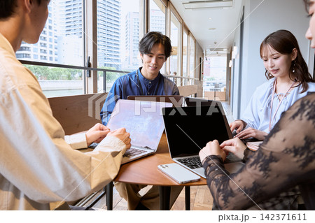 カフェでノートパソコンを使いミーティングをする若いビジネスパーソン カフェでノートパソコンを使いミーティングをする若いビジネスパーソン 142371611