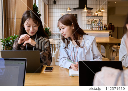 カフェでノートパソコンを見ながら打ち合わせをする二人の若い女性 142371630