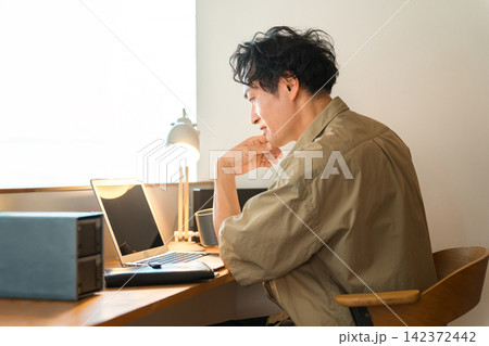 自宅でノートパソコンを使って在宅ワーク,テレワークする中年男性 自宅でノートパソコンを使って在宅ワーク,テレワークする中年男性 142372442
