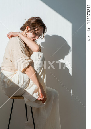 光と影に包まれたナチュラルファッションのおしゃれな女性 光と影に包まれたナチュラルファッションのおしゃれな女性 142373211