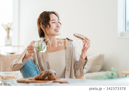 自宅でパン,バゲットで食事を楽しむリラックスタイムの女性 自宅でパン,バゲットで食事を楽しむリラックスタイムの女性 142373378