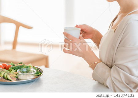 朝食にサラダと温かいスープ,飲み物を楽しむ女性の健康的な食生活 朝食にサラダと温かいスープ,飲み物を楽しむ女性の健康的な食生活 142374132