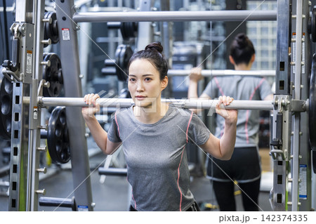 スポーツジムでトレーニングする若い女性 スポーツジムでトレーニングする若い女性 142374335