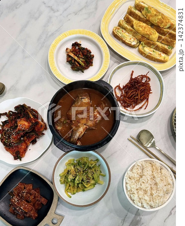 Warm and comforting jibbap (home-cooked Korean meal) with a spread of rice, soup, and banchan, offering a perfect harmony of flavor, tradition, and heartwarming nourishment in every bite. Warm and comforting jibbap (home-cooked Korean meal) with a spread of rice, soup, and banchan, offering a perfect harmony of flavor, tradition, and heartwarming nourishment in every bite. 142374831