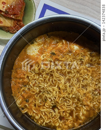 A steaming bowl of ramyeon with chewy noodles, rich and spicy broth, and flavorful toppings like green onions, egg, and vegetables. A quick and satisfying comfort food favorite. A steaming bowl of ramyeon with chewy noodles, rich and spicy broth, and flavorful toppings like green onions, egg, and vegetables. A quick and satisfying comfort food favorite. 142374838