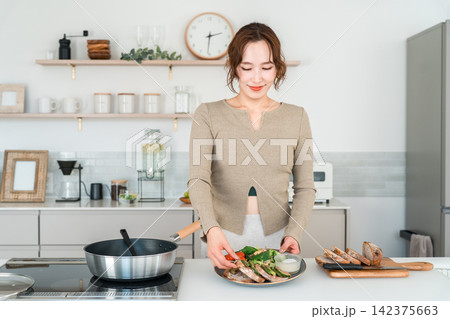 自宅のキッチンで健康的な食事の準備をする女性 自宅のキッチンで健康的な食事の準備をする女性 142375663