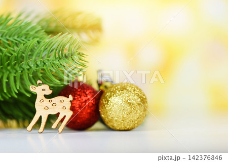 Christmas decoration pine tree with golden red balls and wooden reindeer holiday yellow bokeh background / christmas tree festive xmas winter and Happy New Year object 142376846