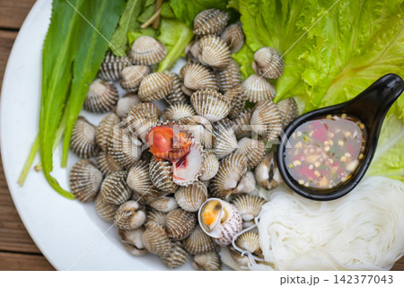 Cockle shellfish seafood plate with fresh vegetable herbs and spices on plate food Cockles background - blood cockle peeled on table with seafood sauce Cockle shellfish seafood plate with fresh vegetable herbs and spices on plate food Cockles background - blood cockle peeled on table with seafood sauce 142377043
