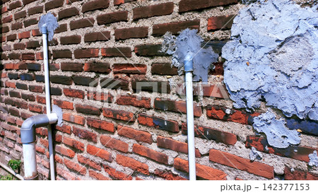 Exterior PVC pipe and cement patch on a brick wall 142377153