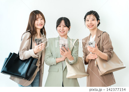 スマートフォンを持って笑顔で並ぶビジネスウーマン3人 142377154