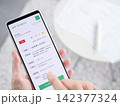 スマホの求人サイトで事務職を探す女性の手元写真（求人検索・転職）スマートフォン画面内はオリジナル制作 142377324
