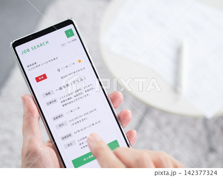 スマホの求人サイトで事務職を探す女性の手元写真(求人検索・転職)スマートフォン画面内はオリジナル制作 スマホの求人サイトで事務職を探す女性の手元写真(求人検索・転職)スマートフォン画面内はオリジナル制作 142377324