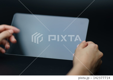 Transparent Tablet Mockup Held by Hands on Dark Background Transparent Tablet Mockup Held by Hands on Dark Background 142377714