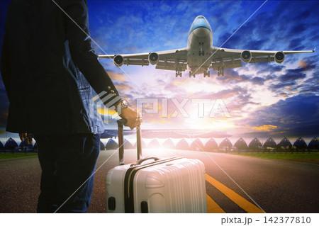 Air Travel Passenger with Suitcase and Landing Jet at Sunset Air Travel Passenger with Suitcase and Landing Jet at Sunset 142377810