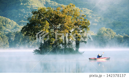Kayaker on Misty Lake with Forest Island at Sunrise 142378137