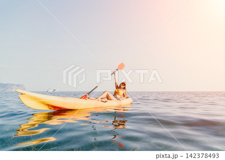 Woman Kayaking Sea Paddle Summer: A woman paddles a yellow kayak in the sea on a sunny day. 142378493