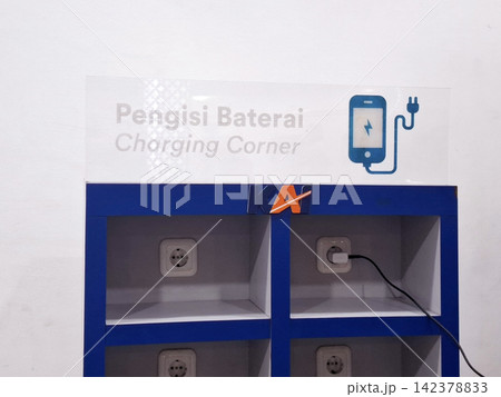 Blue wooden charging station shelf with power sockets for mobile device battery replenishment in public terminal. Blue wooden charging station shelf with power sockets for mobile device battery replenishment in public terminal. 142378833