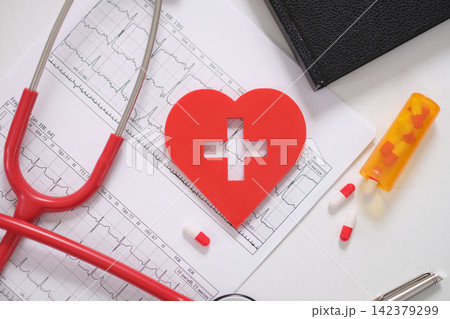Heart with cross and phonendoscope on patient electrocardiogram in clinic closeup 142379299