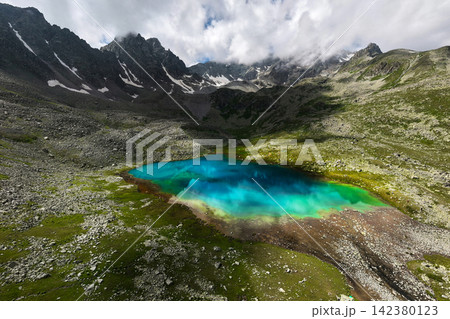 Vibrant turquoise alpine lake in a rocky mountain valley Vibrant turquoise alpine lake in a rocky mountain valley 142380123