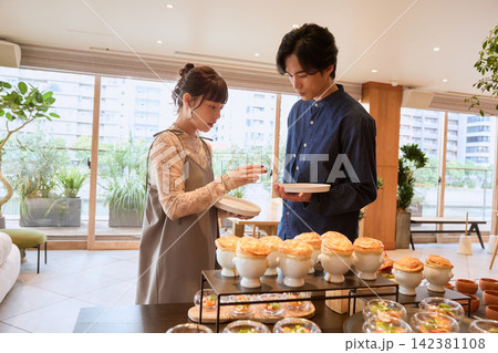 ビュッフェレストランで料理を選ぶ若いカップル ビュッフェレストランで料理を選ぶ若いカップル 142381108