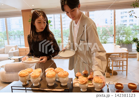 ビュッフェでパイ包みスープや料理を選ぶ若い男女カップル ビュッフェでパイ包みスープや料理を選ぶ若い男女カップル 142381123