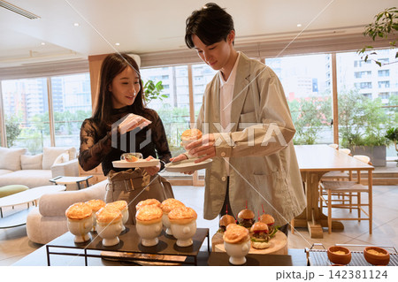 おしゃれなカフェでビュッフェ料理を取り分ける若いカップル おしゃれなカフェでビュッフェ料理を取り分ける若いカップル 142381124