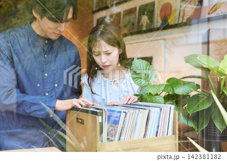 レコードショップでレコードを選ぶ若いカップル レコードショップでレコードを選ぶ若いカップル 142381182