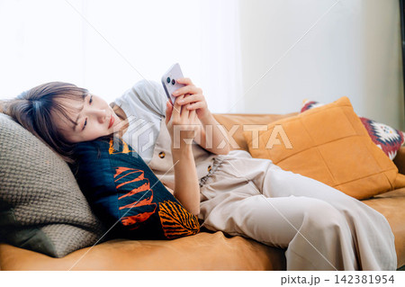 リビングでスマホを使う若い女性 142381954