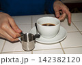 hands adding water to a coffee cup 142382120