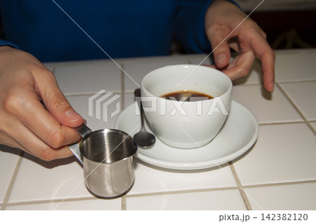 hands adding water to a coffee cup 142382120